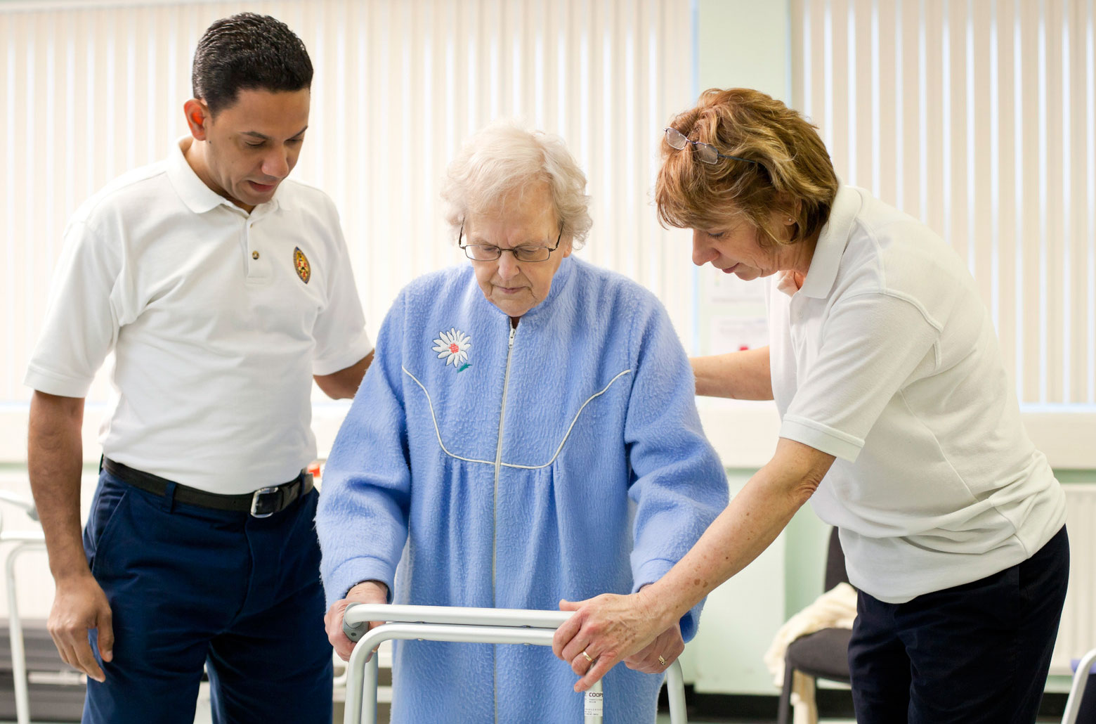 Physios helping woman with walking frame