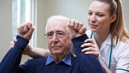 Physio assessing a stroke patient by lifting their arms