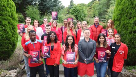 A group of CSP members pose outside, wearing red and holding red posters